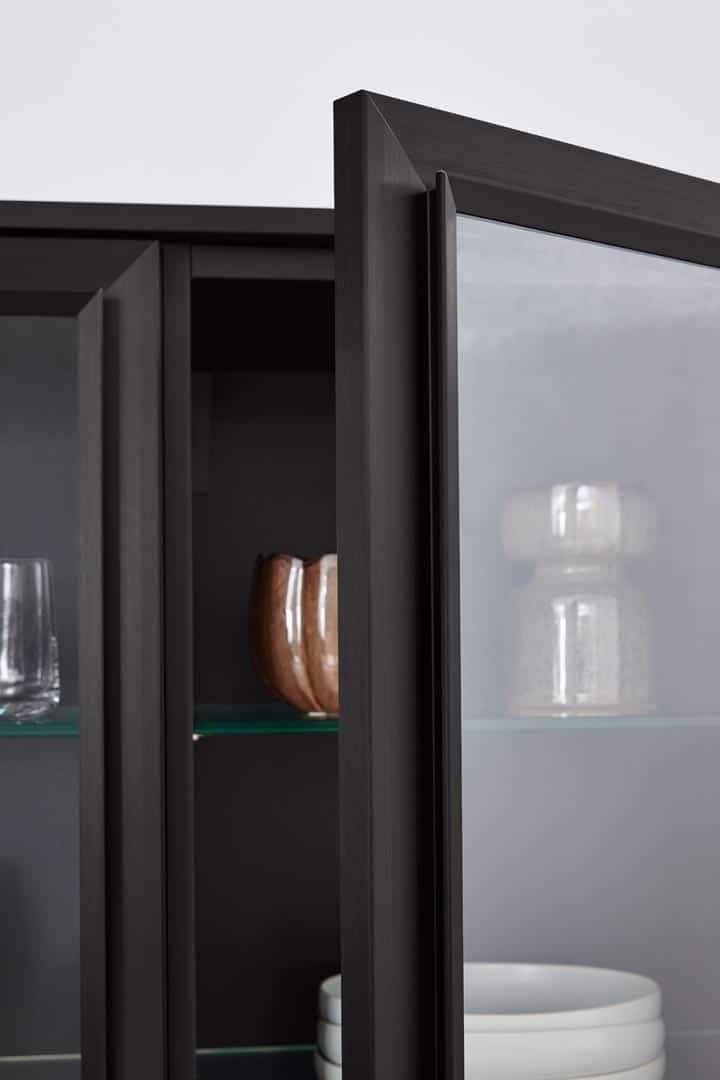 Modernes schwarzes Glasvitrine mit Geschirr und Dekorationen.