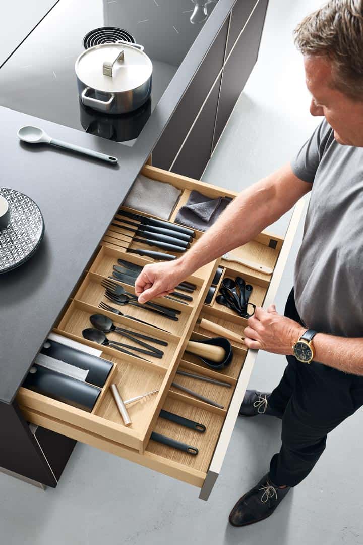 Mann organisiert Besteckschublade in moderner Küche