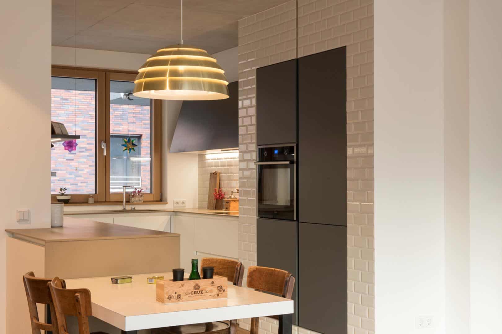 Moderne Küche mit Esstisch und hängender Lampe.
