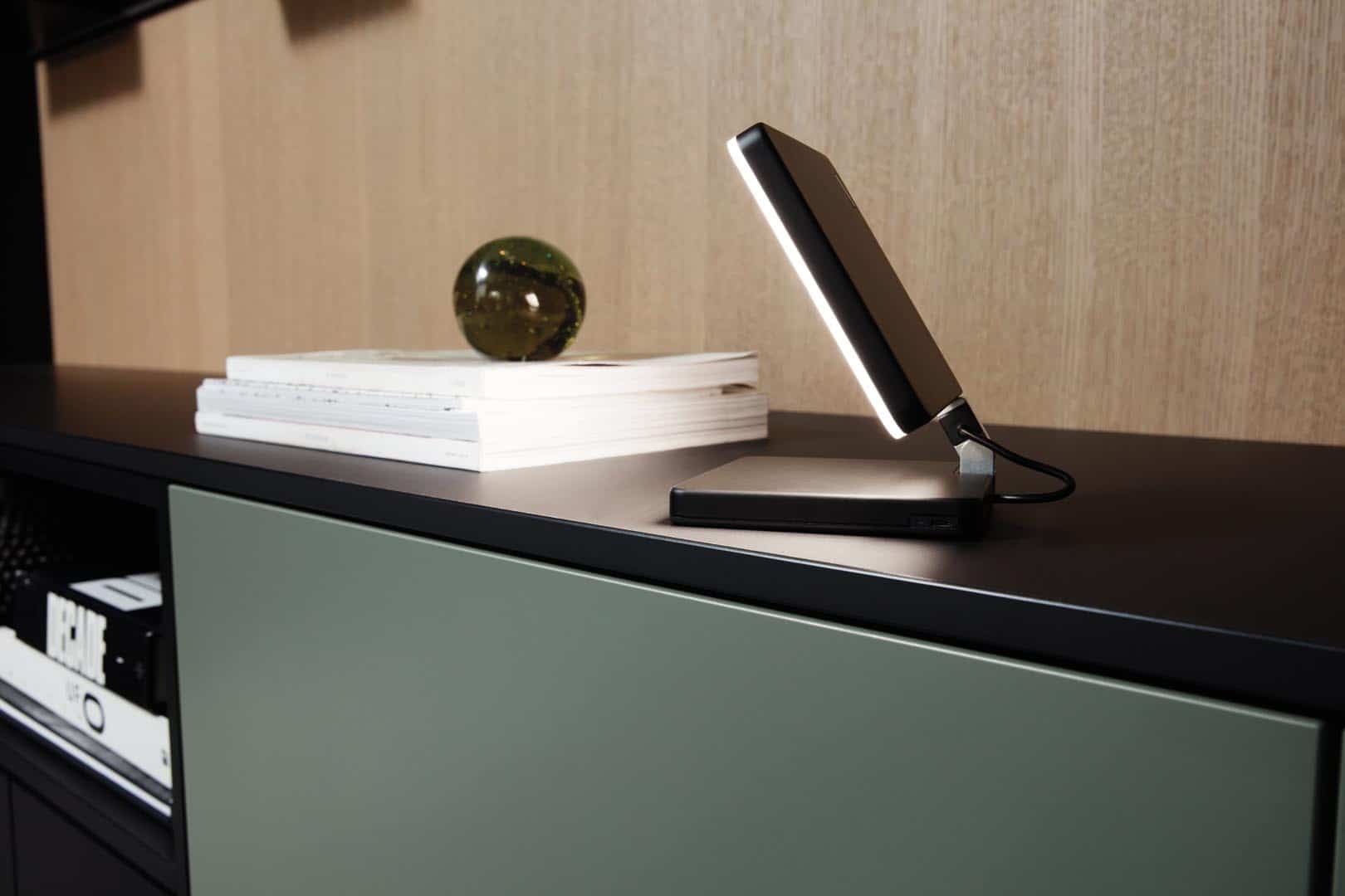 Moderne Tischlampe neben Bücherstapel auf Sideboard