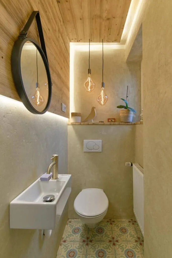 Modernes WC mit Spiegel, Waschbecken und Hängelampen.