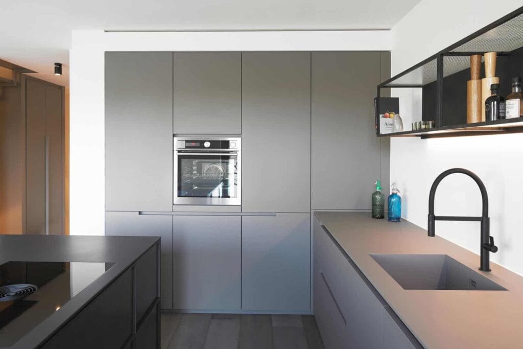 Moderne graue Küche mit integriertem Ofen und Waschbecken.