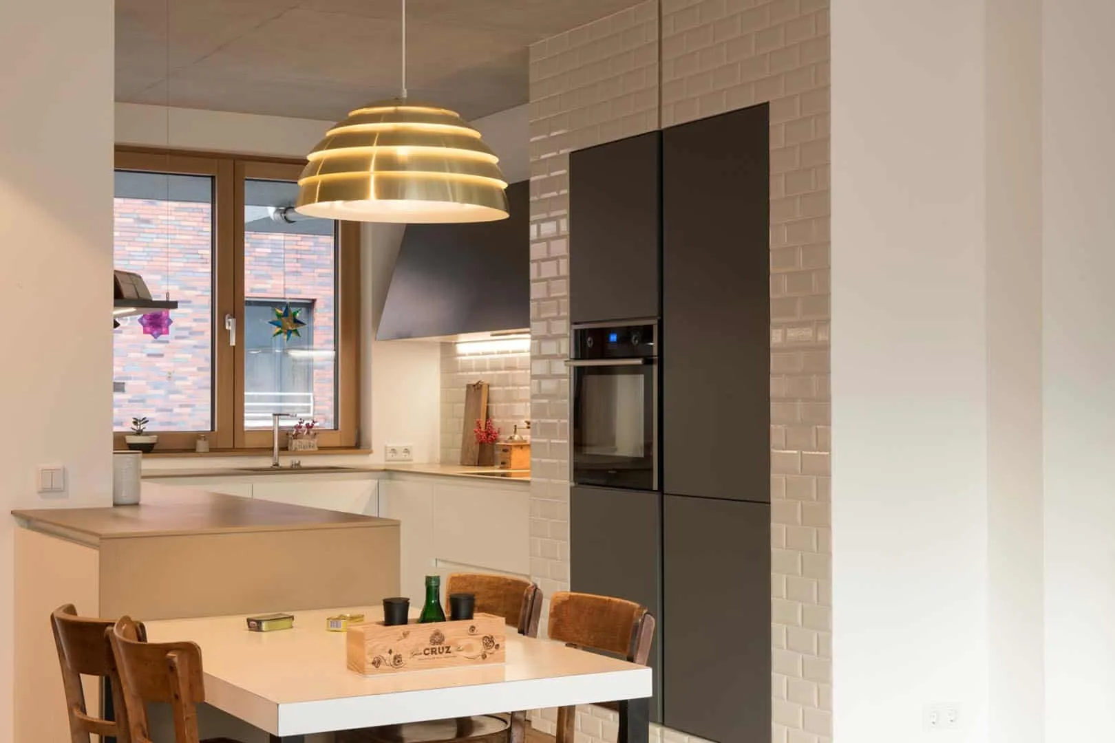 Moderne Küche mit Esstisch und hängender Lampe.